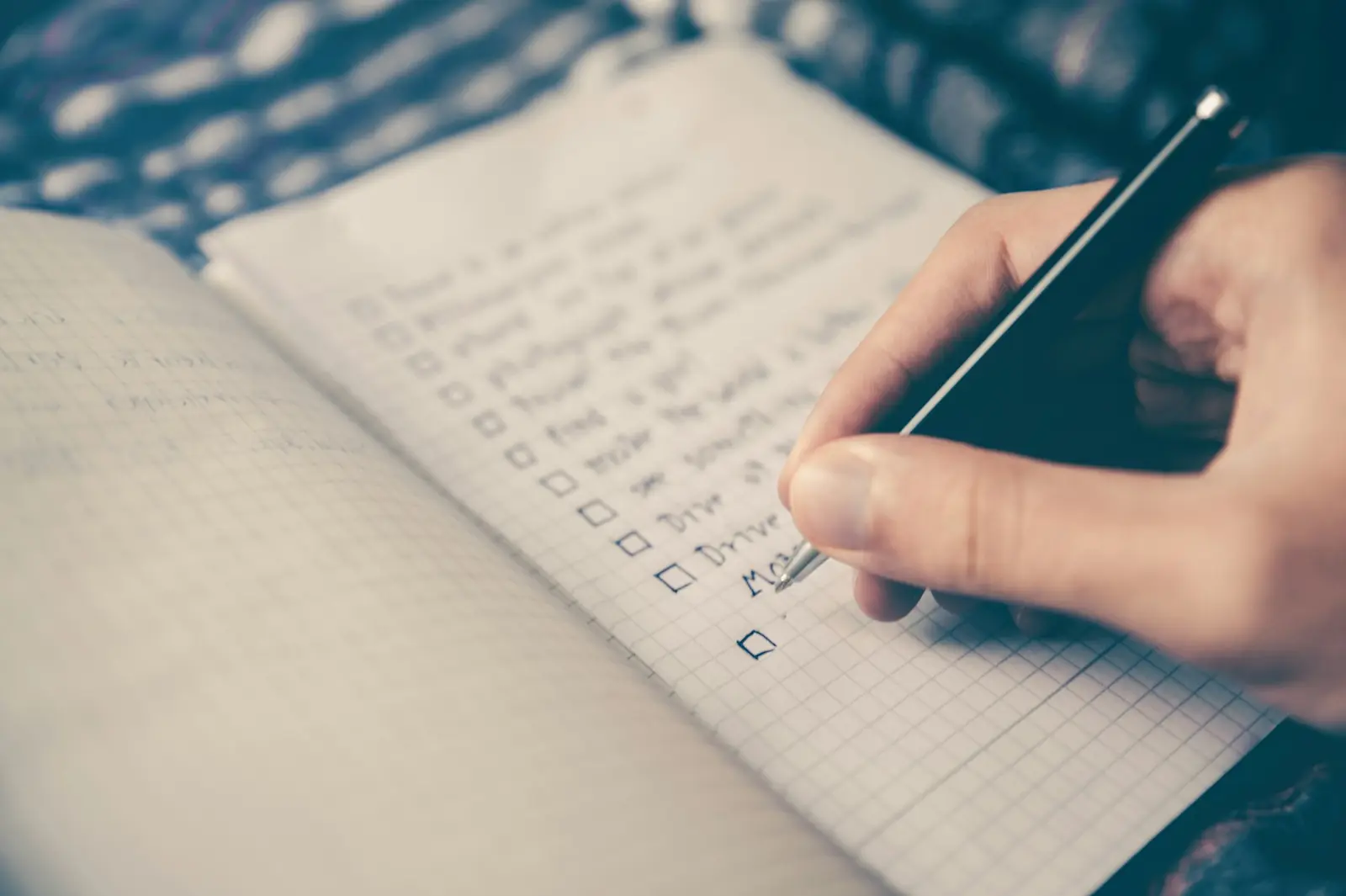 A desk planner open on a calendar, with a notebook and coffee beside a keyboard